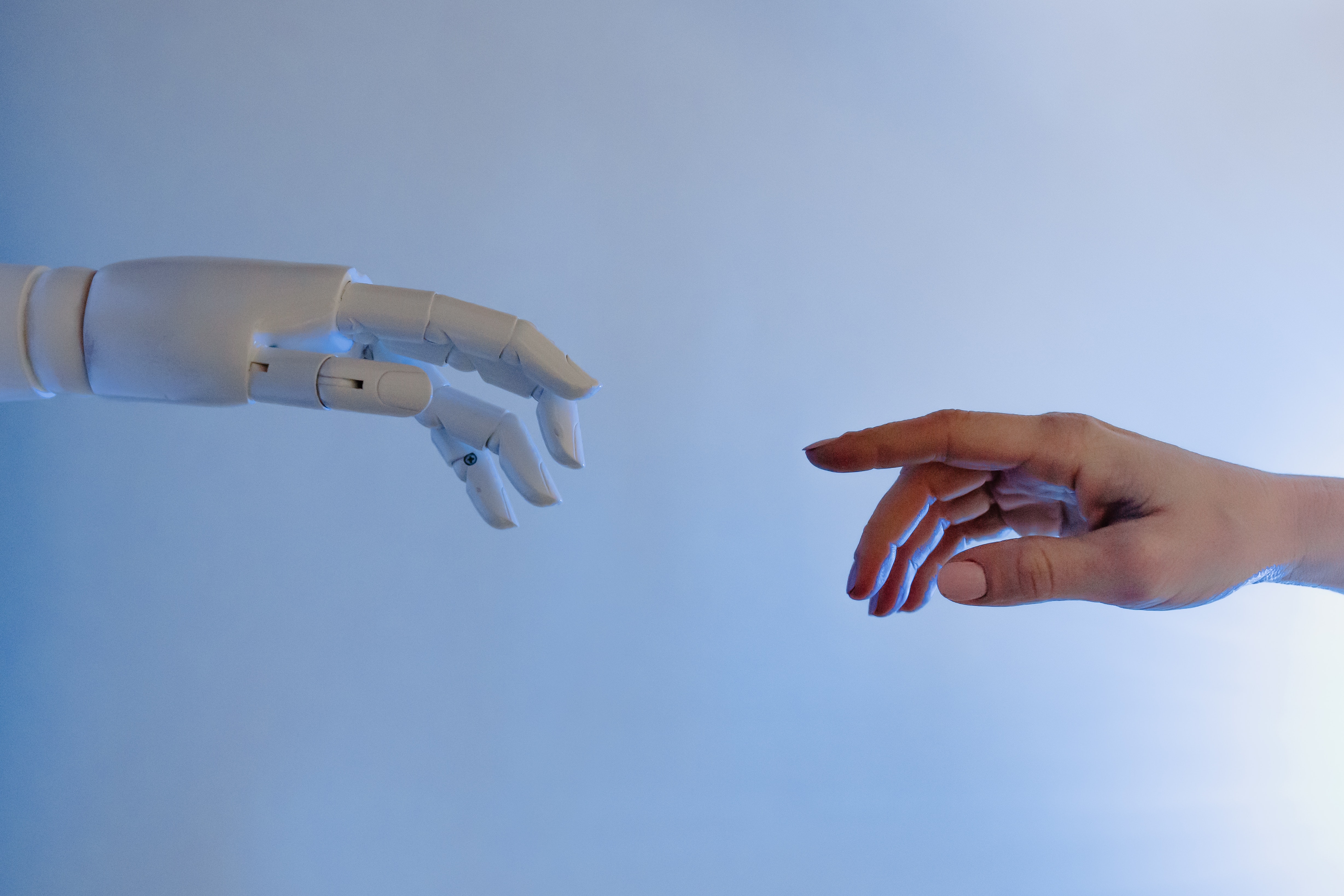Robotic Hand and Human Hand Reaching Out to Touch Fingers