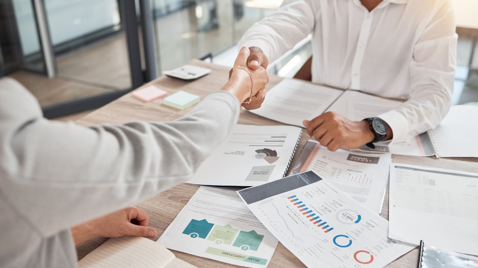 A hiring manager shakes hands with a new hire, illustrating a successful onboarding experience.